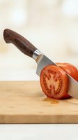 Fresh red tomato sliced with chef knife on wooden cutting board. Cooking preparation, food preparation, kitchen utensil, culinary ingredient for recipes and meal planning.