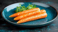 Fresh orange carrots with green leaves on textured turquoise ceramic plate against dark background. Raw organic vegetables for healthy cooking.