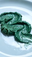 Spirulina or chlorella powder spread on white plate, nutrient-rich superfood ingredient for healthy eating, wellness and nutrition concepts.