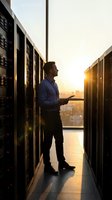 IT administrator monitoring server room at sunset with tablet in modern data center for technology infrastructure management.