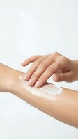 Woman's hand applying moisturizing cream on arm against white background. Skincare routine, cosmetics product testing, beauty and wellness concept for dermatology and cosmetic advertising.