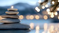 Balanced stone pyramid with bokeh lights and pine branches reflecting in water creates serene spa atmosphere against blurred mountain landscape.