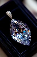 Marquise cut crystal pendant with pavé diamonds on luxury velvet background showcasing brilliant light dispersion and faceted reflections in clear gemstone jewelry.
