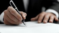 Businessman signing contract or legal document with fountain pen on white paper, close-up view of male hand in formal suit writing signature.