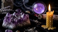 Mystical purple amethyst crystals with glowing candle and crystal ball creating magical atmosphere for spiritual practices and meditation rituals.