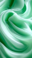 Soft swirls of mint green cream create smooth flowing curves and waves in macro photography, highlighting delicate texture and gradient shading for cosmetic and food designs.