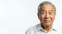 Senior Asian man with gray hair wearing light blue button-up shirt, smiling warmly at camera against white background. Suitable for healthcare, business, corporate, and lifestyle editorial use.