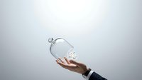 Hand holding transparent glass globe with glowing light bulb inside, representing innovation, ideas, sustainability, and renewable energy solutions for business and technology concepts.