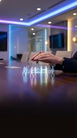 Businessman hand protecting holographic team figures on modern office desk with LED lighting for insurance and leadership concepts.