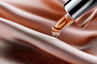Luxury cosmetic dropper with golden serum drop falling on silky rose gold fabric background, elegant skincare product photography for beauty ads.