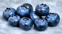 Fresh ripe blueberries with natural bloom coating on gray concrete background, macro food photography showing texture and details of berries.