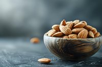 Fresh whole almonds in wooden bowl on dark background with selective focus and copy space. Natural healthy snack and ingredient for cooking.