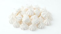 Heap of white and cream meringue cookies with peaked tops on white background, isolated for bakery, confectionery, dessert, and food design projects.