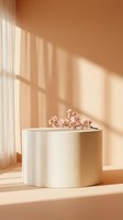 Minimalist cream cylindrical podium with delicate cherry blossom branch in warm sunlight shadows for product display and spring branding concepts.