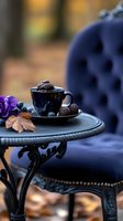 Dark chocolate truffles in black coffee cup on vintage table with navy velvet chair, purple flowers and autumn leaves creating moody atmospheric composition.
