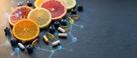 Fresh citrus fruits with vitamin supplements and blueberries on dark slate background promoting healthy lifestyle and natural nutrition concepts.