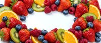 Fresh mixed berries and fruit slices arranged in heart shape on white background. Colorful assortment of strawberries, blueberries, raspberries, kiwi and orange.