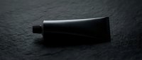 Matte black cosmetic tube on dark stone surface, minimalist skincare packaging mockup for branding, beauty product presentation.