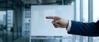 Business professional pointing finger at blank whiteboard in modern office conference room for presentation and meeting concepts.