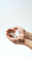 Cupped hands gently holding delicate iridescent butterfly on white background symbolizing care, protection, transformation and fragile beauty.