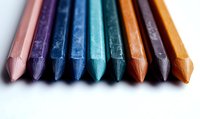 Colorful wooden pencils arranged in row showing tips, macro photography with selective focus on textured drawing tools against white background.