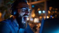 Young bearded man with glasses and headphones singing or shouting with passion in urban night setting with bokeh lights, suitable for music, entertainment, and lifestyle content.