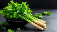 Fresh parsley roots with bright green leaves on dark background, raw organic vegetables in rustic setting for cooking and food photography.