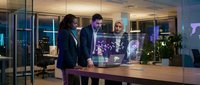 Three diverse business professionals collaborating with holographic technology display in modern office environment during evening hours.