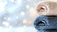 Soft folded towels in beige and blue colors on blurred bokeh background with sparkles and copy space. Spa and wellness concept for relaxation.