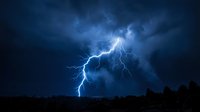 Dramatic lightning strike illuminates dark storm clouds during intense thunderstorm at night, capturing raw power of nature for weather and atmospheric design projects.