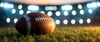 American football on grass field with stadium lights creating bokeh background for sports and recreation themes.