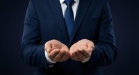 Professional businessman in navy suit with open palms gesture presenting concept on dark background for corporate presentations and business solutions.