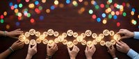 Business team collaboration with glowing lightbulbs representing innovative ideas and creative solutions on wooden table with colorful bokeh lights.