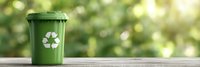 Green recycling bin with recycle symbol on wooden surface against blurred natural bokeh background, eco-friendly waste management concept for environmental sustainability.
