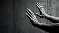 Dramatic black and white hands reaching upward against textured concrete wall background expressing hope, prayer, surrender or plea for help.