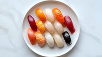 Assorted sushi nigiri set with salmon, tuna, shrimp and eel on white plate. Fresh Japanese cuisine platter for restaurant menu and food photography.