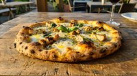 Freshly baked wood-fired pizza with melted cheese, charred crust, and fresh basil garnish served on wooden board in restaurant setting.