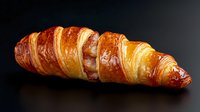 Fresh baked golden brown croissant with flaky layered texture and glossy surface on dark background, dramatic lighting highlights buttery pastry details.
