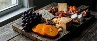 Gourmet cheese and charcuterie board with grapes, nuts, crackers and cured meats on rustic wooden platter for entertaining and wine pairing occasions.