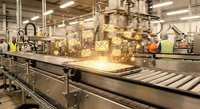 Automated robotic arm handling cardboard boxes on industrial conveyor belt system in modern warehouse facility with bright lighting and safety equipment.