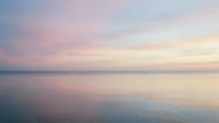 Serene dawn seascape with soft pastel sky reflecting on calm ocean waters, ideal for wellness, travel, and lifestyle design projects.