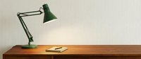 Wooden desk with green adjustable task lamp and notebook, minimalist workspace setup for office, study, or creative work environments.