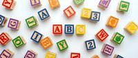 Colorful wooden alphabet blocks scattered on white background featuring letters and numbers for educational play and learning activities.