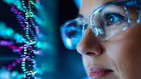 Young female scientist in protective glasses observing genetic data visualization, DNA helix structure displayed on futuristic screen with neon blue lighting.