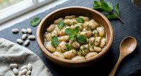 Healthy white bean salad with fresh herbs in wooden bowl on dark slate background. Nutritious legume dish perfect for Mediterranean diet and vegetarian meals.