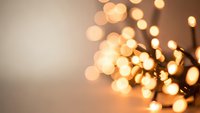 Warm golden bokeh lights creating soft glowing circles against neutral background for holiday decorations and festive atmosphere designs.