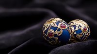 Luxurious blue and gold Christmas ornaments with intricate floral patterns and red gemstones on dark velvet background, elegant holiday decoration detail.