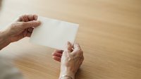 Hands holding blank white card on wooden surface for mockup, branding, or business presentation purposes.