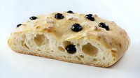 Freshly baked focaccia bread with black olives, showing airy texture and golden crust on white background. Perfect for food photography.