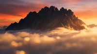 Dramatic mountain peak emerging from golden clouds at sunset with vibrant orange and pink sky creating mystical alpine landscape for outdoor adventure themes.